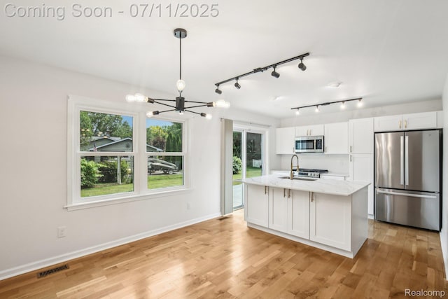 10746 Winthrop, Pinckney, MI 48169 - kitchen with stainless steel appliances, a chandelier, white cabinets, light wood-style flooring, and light stone countertops