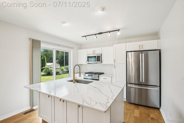 10746 Winthrop, Pinckney, MI 48169 - kitchen featuring appliances with stainless steel finishes, white cabinetry, light wood finished floors, a center island with sink, and light stone counters