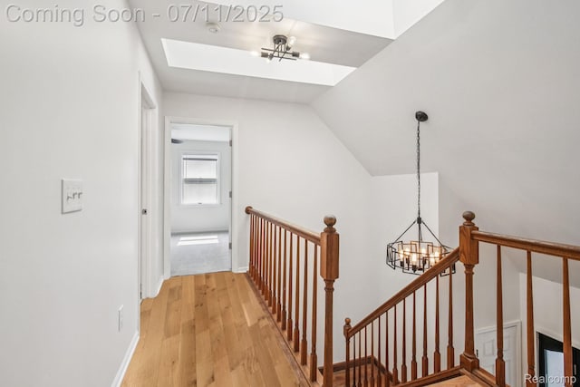 10746 Winthrop, Pinckney, MI 48169 - corridor with a chandelier, an upstairs landing, a skylight, light wood finished floors, and vaulted ceiling