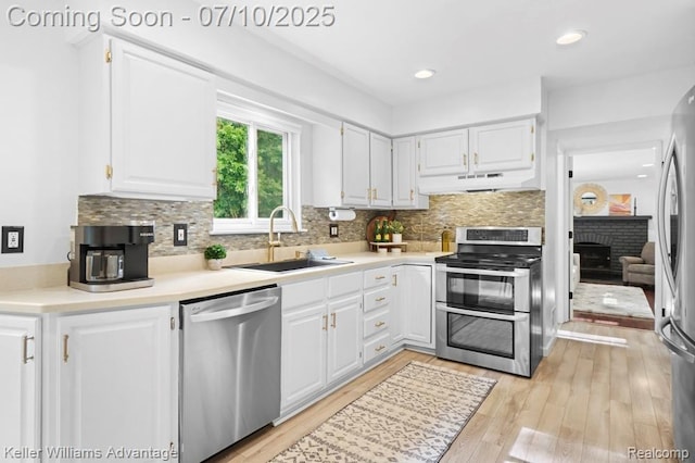9157 Hackberry Ave, Plymouth, MI 48170 - kitchen featuring appliances with stainless steel finishes, under cabinet range hood, white cabinetry, backsplash, and light wood-type flooring