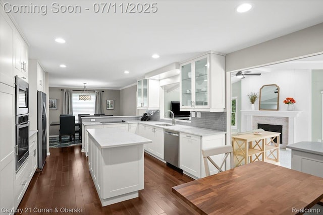 42369 Crestview Cir, Northville, MI 48168 - kitchen with stainless steel appliances, glass insert cabinets, a fireplace, white cabinetry, and a peninsula