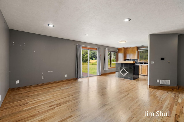 8201 Crocker Rd, Holton, MI 49425 - unfurnished living room with light wood-style floors, recessed lighting, and a textured ceiling