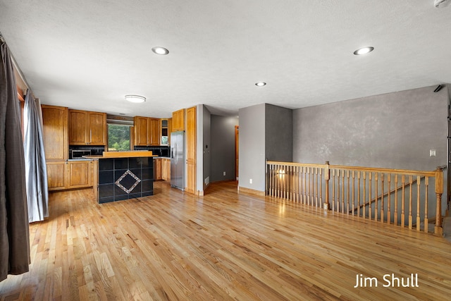 8201 Crocker Rd, Holton, MI 49425 - kitchen featuring stainless steel refrigerator with ice dispenser, light wood finished floors, a center island, brown cabinetry, and recessed lighting