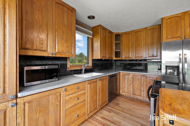 8201 Crocker Rd, Holton, MI 49425 - kitchen with appliances with stainless steel finishes, brown cabinets, glass insert cabinets, light wood-type flooring, and light countertops