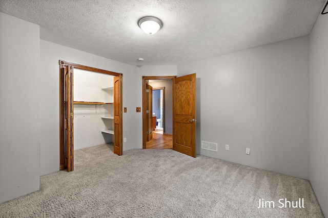 8201 Crocker Rd, Holton, MI 49425 - unfurnished bedroom featuring carpet floors, a walk in closet, a textured ceiling, and a closet
