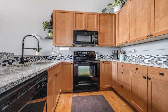 600 Broadway Ave NW Unit 402, Grand Rapids, MI 49504 - kitchen featuring black appliances, light wood-type flooring, decorative backsplash, and light stone countertops