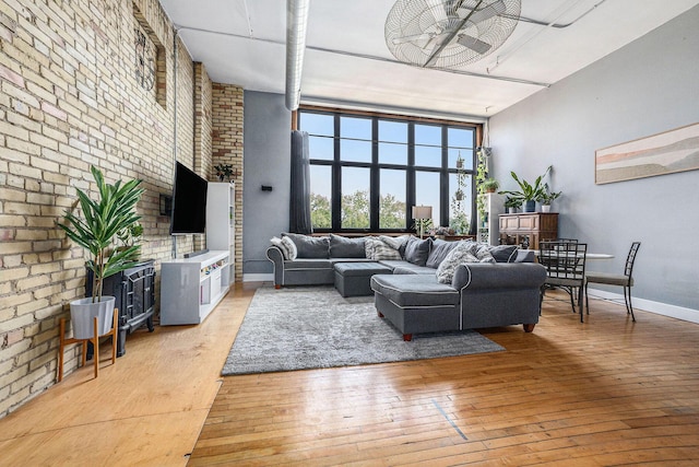 600 Broadway Ave NW Unit 402, Grand Rapids, MI 49504 - living room featuring brick wall, light wood finished floors, a ceiling fan, and a high ceiling