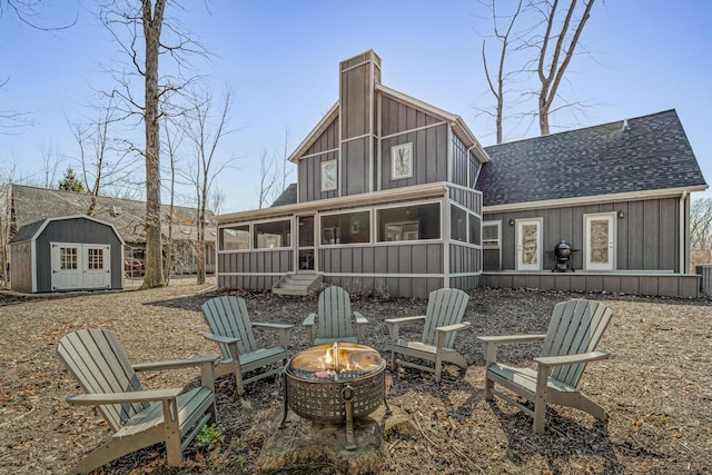 32 Walden Way, New Buffalo, MI 49117 - back of property featuring a sunroom, a fire pit, roof with shingles, board and batten siding, and a chimney