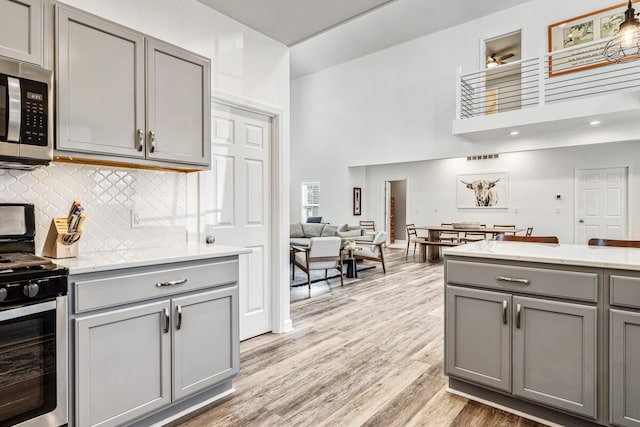 32 Walden Way, New Buffalo, MI 49117 - kitchen with gray cabinets, stainless steel appliances, light wood-style flooring, a high ceiling, and backsplash
