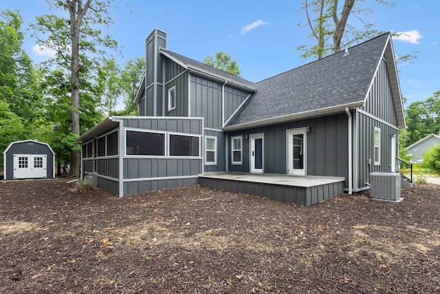 32 Walden Way, New Buffalo, MI 49117 - rear view of property featuring a shingled roof, a sunroom, board and batten siding, a chimney, and a storage shed