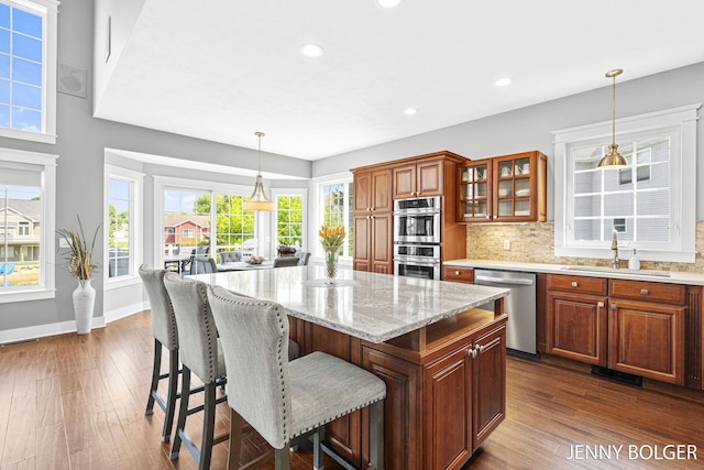 7066 Country Springs Dr SW, Byron Center, MI 49315 - kitchen with appliances with stainless steel finishes, dark wood-style floors, a kitchen bar, glass insert cabinets, and recessed lighting