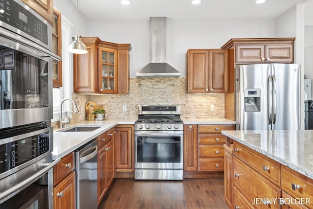 7066 Country Springs Dr SW, Byron Center, MI 49315 - kitchen with wall chimney range hood, stainless steel appliances, brown cabinetry, light stone counters, and recessed lighting