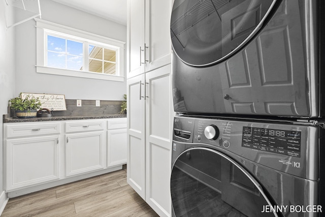 7066 Country Springs Dr SW, Byron Center, MI 49315 - laundry room featuring stacked washer / dryer, cabinet space, and light wood-type flooring