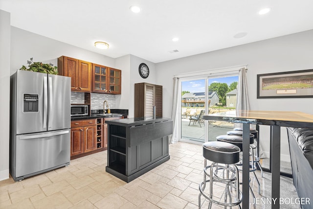 7066 Country Springs Dr SW, Byron Center, MI 49315 - kitchen featuring stainless steel appliances, dark countertops, stone tile floors, recessed lighting, and brown cabinetry