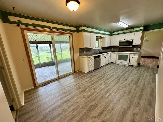 4650 Village Dr, Saginaw, MI 48638 - kitchen with stainless steel appliances, white cabinetry, dark wood-style flooring, and decorative backsplash