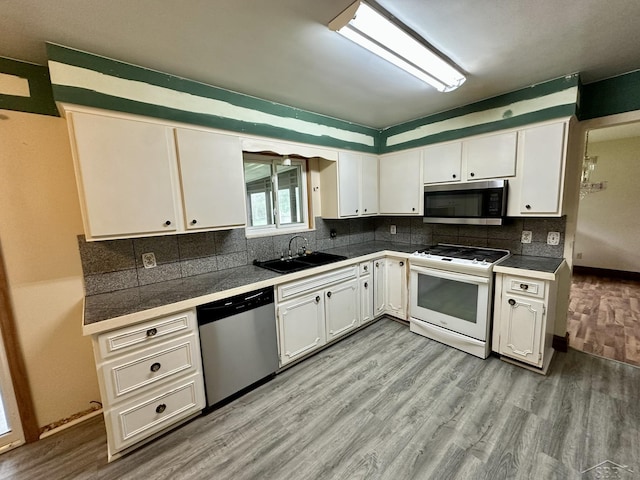 4650 Village Dr, Saginaw, MI 48638 - kitchen with appliances with stainless steel finishes, white cabinetry, light wood-type flooring, and backsplash