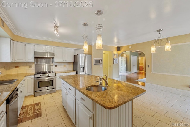 8400 Oak Shade Ct, Davison, MI 48423 - kitchen with arched walkways, light tile patterned floors, stainless steel appliances, decorative backsplash, and an island with sink