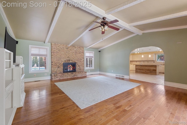 8400 Oak Shade Ct, Davison, MI 48423 - unfurnished living room with a ceiling fan, wood-type flooring, arched walkways, and a brick fireplace