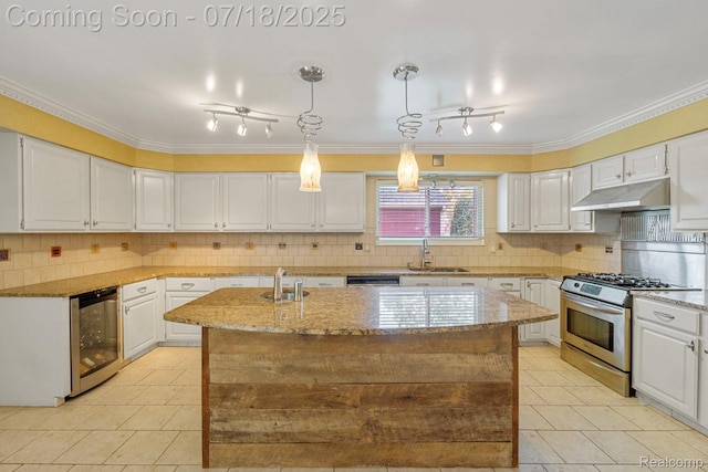 8400 Oak Shade Ct, Davison, MI 48423 - kitchen featuring light tile patterned floors, gas range, rail lighting, light stone countertops, and crown molding