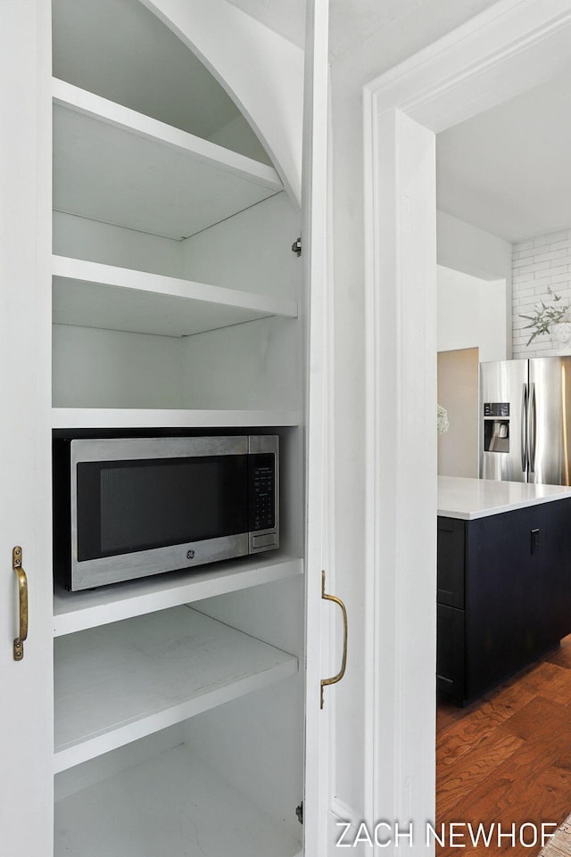 334 Washington Blvd, Holland, MI 49423 - kitchen view of appliances with stainless steel finishes, dark cabinetry, wood finished floors, arched walkways, and light countertops