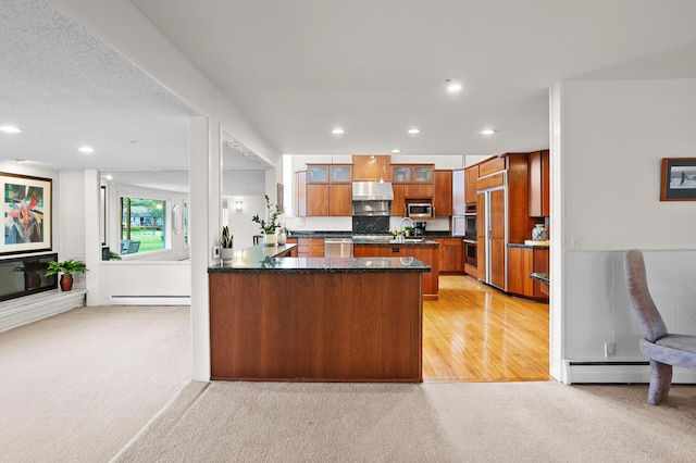 2323 Solano Dr, Wolverine Lake, MI 48390 - kitchen with under cabinet range hood, light colored carpet, stainless steel appliances, brown cabinetry, and a peninsula