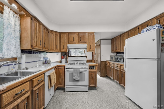 318 E Adrian St, Blissfield, MI 49228 - kitchen with white appliances, under cabinet range hood, light countertops, brown cabinetry, and light colored carpet