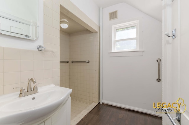 445 Prince St SE, Grand Rapids, MI 49507 - bathroom with wood finished floors, tile walls, and vaulted ceiling