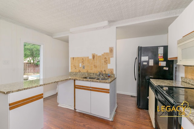 445 Prince St SE, Grand Rapids, MI 49507 - kitchen featuring white microwave, black / electric stove, dark wood-style floors, decorative backsplash, and white cabinets