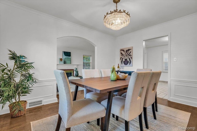 4800 Bishop St, Detroit, MI 48224 - dining space featuring arched walkways, a chandelier, crown molding, wood finished floors, and a glass covered fireplace