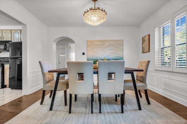 4800 Bishop St, Detroit, MI 48224 - dining area with arched walkways, wood finished floors, a chandelier, ornamental molding, and a decorative wall