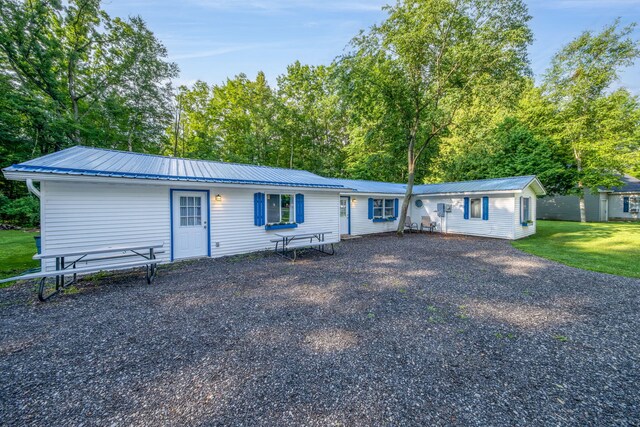 1051 Vallado Dr, Weidman, MI 48893 - view of front of house featuring a metal roof, a front yard, driveway, and view of wooded area