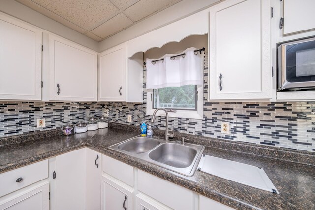 1051 Vallado Dr, Weidman, MI 48893 - kitchen with a paneled ceiling, white cabinetry, dark countertops, and tasteful backsplash