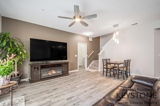 3508 River Run St, Wyoming, MI 49418 - living room with stairway, wood finished floors, a ceiling fan, and a glass covered fireplace