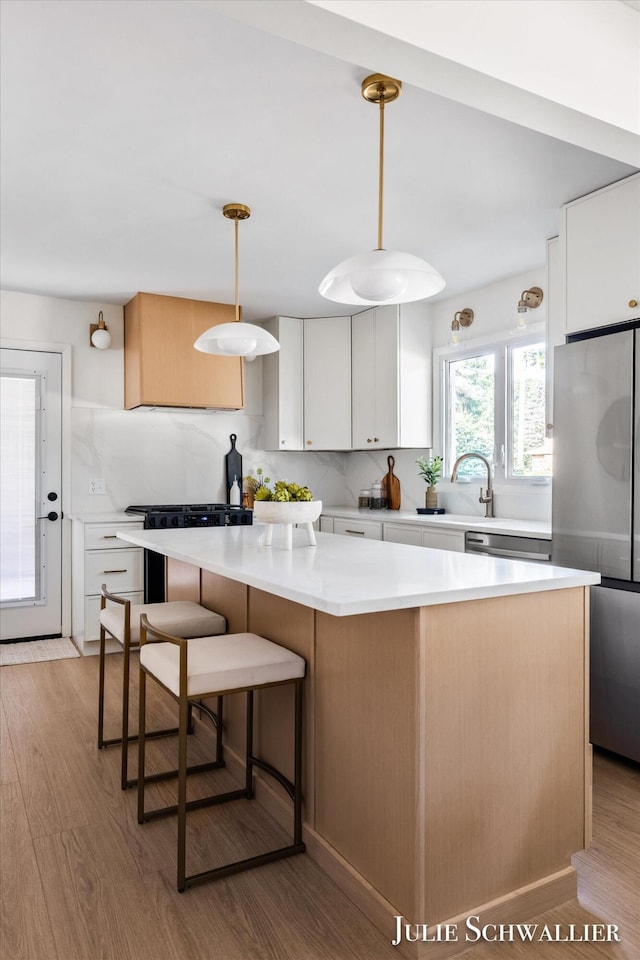 751 Old Gate Rd NW, Grand Rapids, MI 49504 - kitchen featuring appliances with stainless steel finishes, light wood-type flooring, a kitchen island, light countertops, and white cabinets