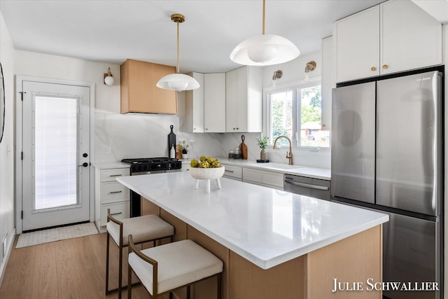 751 Old Gate Rd NW, Grand Rapids, MI 49504 - kitchen with stainless steel appliances, decorative backsplash, white cabinets, light wood-style flooring, and a kitchen bar
