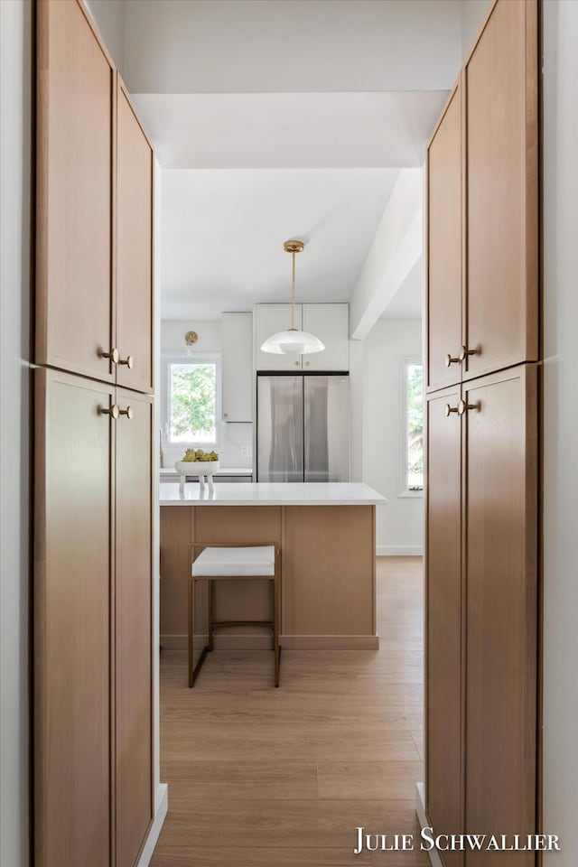 751 Old Gate Rd NW, Grand Rapids, MI 49504 - kitchen featuring stainless steel refrigerator, light wood-style flooring, light countertops, a peninsula, and hanging light fixtures