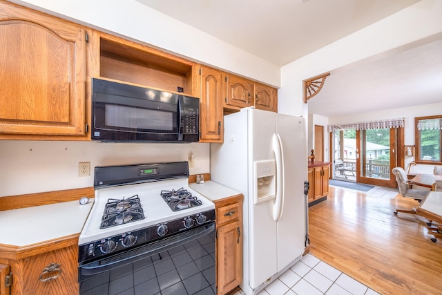 616 N Lincoln Ave, Lakeview, MI 48850 - kitchen with range with gas cooktop, black microwave, white fridge with ice dispenser, light countertops, and brown cabinetry