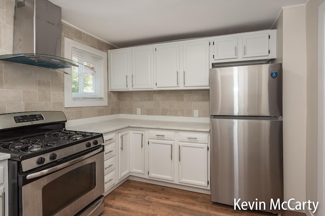 214 Bradford St NE, Grand Rapids, MI 49503 - kitchen with appliances with stainless steel finishes, wall chimney range hood, light countertops, white cabinets, and backsplash