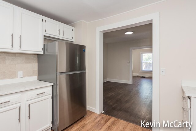 214 Bradford St NE, Grand Rapids, MI 49503 - kitchen featuring freestanding refrigerator, light wood-style flooring, backsplash, and white cabinetry