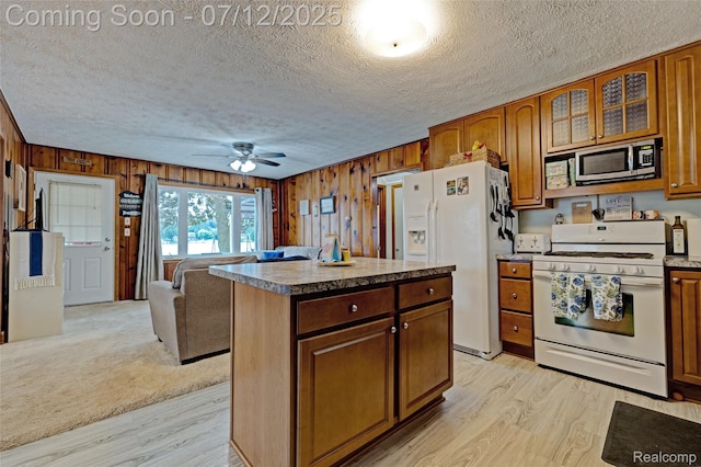1962 Lake Pointe Dr, Ortonville, MI 48462 - kitchen featuring white appliances, light wood-type flooring, a textured ceiling, wooden walls, and a ceiling fan