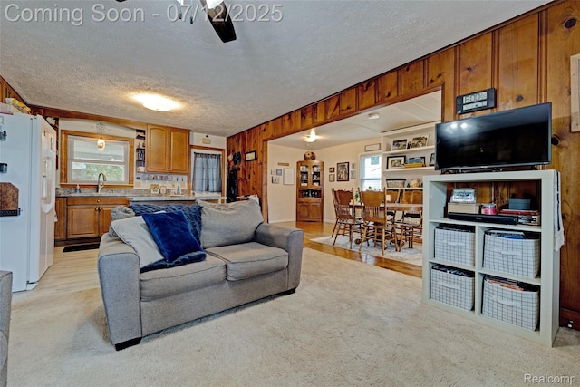 1962 Lake Pointe Dr, Ortonville, MI 48462 - living area featuring a textured ceiling, wood walls, light carpet, and ceiling fan