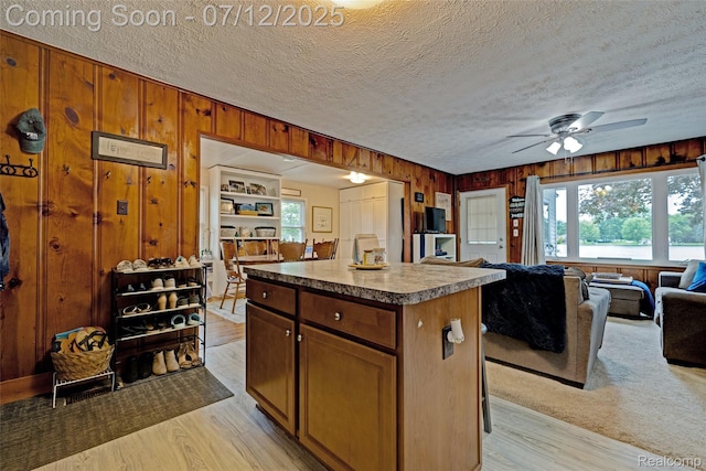 1962 Lake Pointe Dr, Ortonville, MI 48462 - kitchen featuring open floor plan, wood walls, light wood-style floors, a center island, and ceiling fan