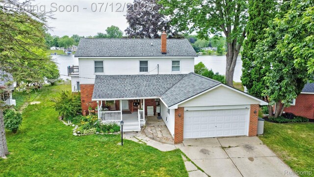 1962 Lake Pointe Dr, Ortonville, MI 48462 - traditional-style house with covered porch, brick siding, a garage, and a front yard