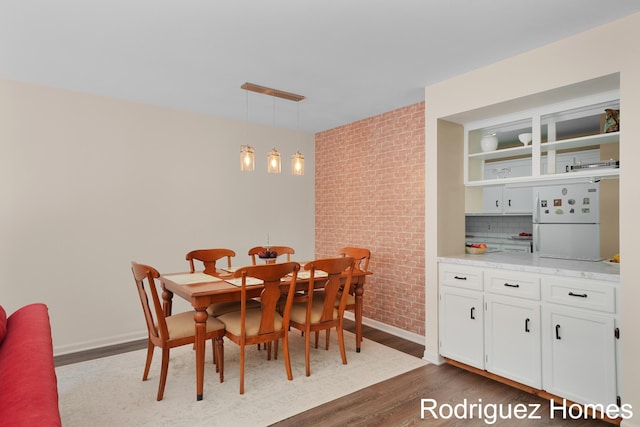 2106 Cranbrook Dr NE, Grand Rapids, MI 49505 - dining room featuring dark wood finished floors and brick wall