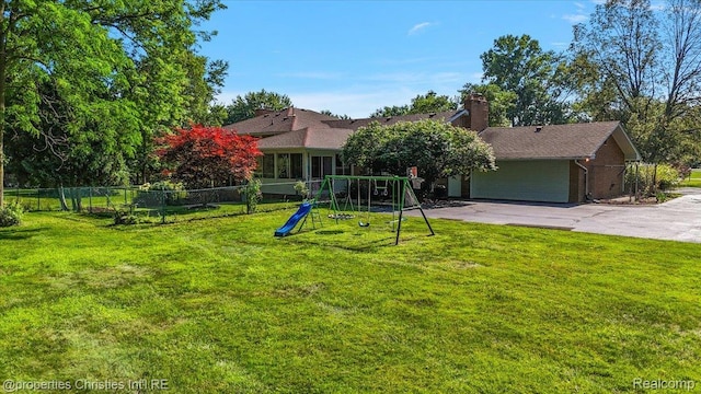 30700 Marimoor St, Beverly Hills, MI 48025 - back of house featuring a playground, asphalt driveway, a garage, and a chimney