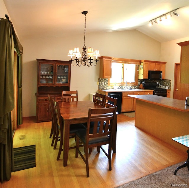 10010 Orchard Ridge Ct, Holly, MI 48442 - dining area with a chandelier, vaulted ceiling, and light wood finished floors