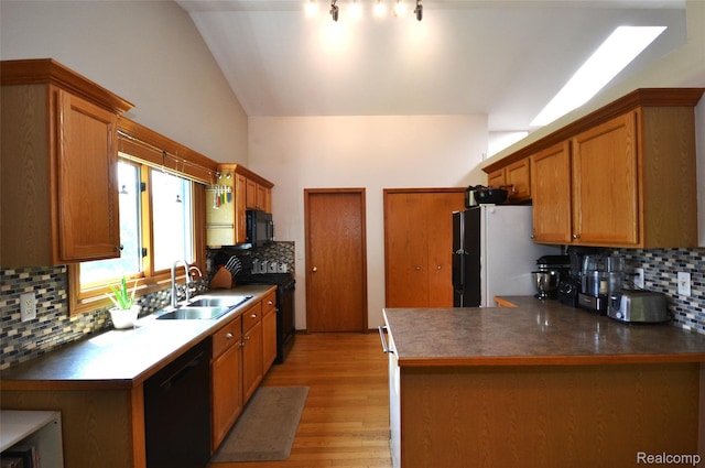 10010 Orchard Ridge Ct, Holly, MI 48442 - kitchen featuring black appliances, tasteful backsplash, vaulted ceiling, light wood-type flooring, and a peninsula