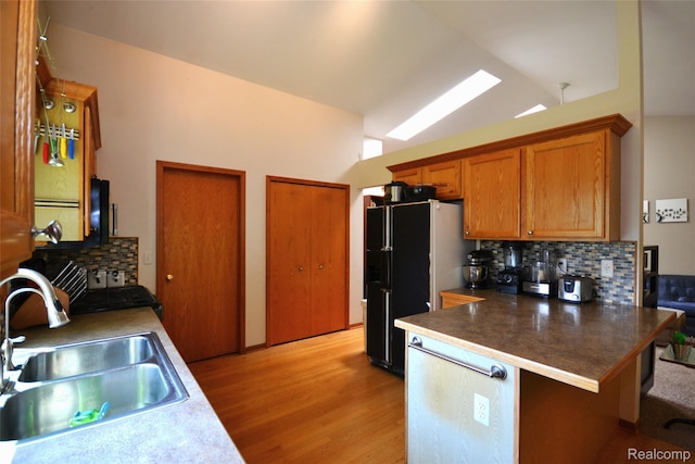 10010 Orchard Ridge Ct, Holly, MI 48442 - kitchen featuring light wood-style flooring, freestanding refrigerator, decorative backsplash, a peninsula, and brown cabinets