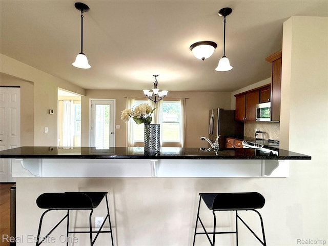 750 Dewars St, Howell, MI 48843 - kitchen with stainless steel appliances, decorative light fixtures, decorative backsplash, a kitchen bar, and a peninsula