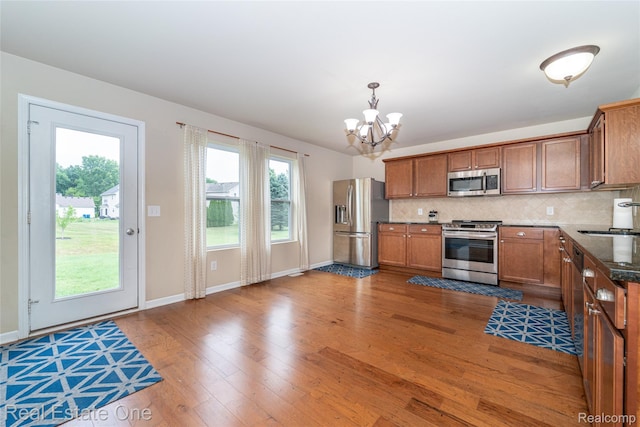 750 Dewars St, Howell, MI 48843 - kitchen with stainless steel appliances, a chandelier, wood finished floors, and backsplash